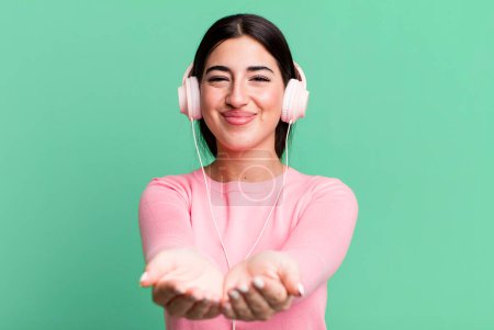 Foto de Smiling happily with friendly and  offering and showing a concept. listening music with headphones - Imagen libre de derechos