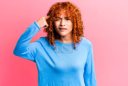 Photo for Redhair pretty woman feeling confused and puzzled, showing you are insane, crazy or out of your mind - Royalty Free Image