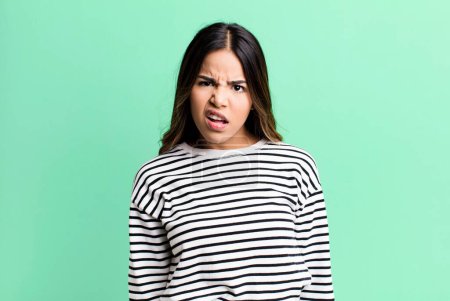 Photo for Hispanic pretty woman feeling puzzled and confused, with a dumb, stunned expression looking at something unexpected - Royalty Free Image