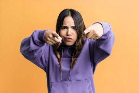 Téléchargez les photos : Hispanique jolie femme pointant vers l'avant à la caméra avec les deux doigts et l'expression en colère, vous disant de faire votre devoir - en image libre de droit