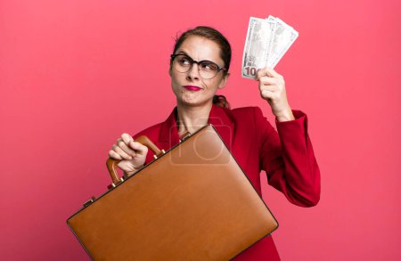 Téléchargez les photos : Young adult pretty businesswoman with a suitcase and bills - en image libre de droit