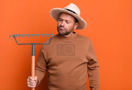 Téléchargez les photos : Middle age man farmer with a rake sport coach concept with a soccer ball - en image libre de droit