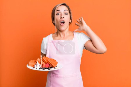 Photo for Pretty blonde woman screaming with hands up in the air. home made waffles concept - Royalty Free Image