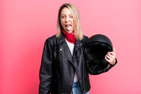 Photo for Pretty blonde woman with cheerful and rebellious attitude, joking and sticking tongue out. motorbike rider and helmet concept - Royalty Free Image