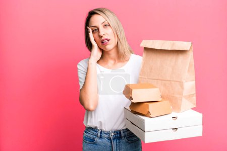 Photo for Pretty blonde woman feeling bored, frustrated and sleepy after a tiresome. paper fast food take away packages - Royalty Free Image