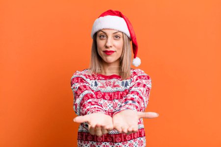 Photo for Pretty blonde woman smiling happily with friendly and  offering and showing a concept. christmas and santa hat concept - Royalty Free Image