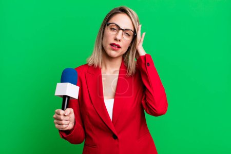 Foto de Pretty blonde woman feeling bored, frustrated and sleepy after a tiresome. presenter or journalist with a microphone - Imagen libre de derechos