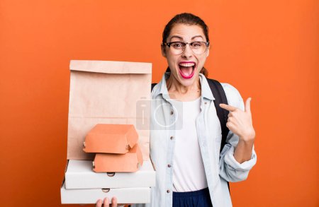 Foto de Una mujer bastante hispana sintiéndose feliz y señalándose a sí misma con una emoción. entrega comida rápida take away concepto - Imagen libre de derechos
