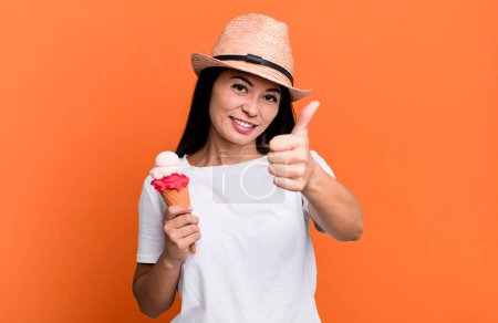 Téléchargez les photos : Hispanique jolie femme se sentant fière, souriant positivement avec les pouces levés. crème glacée et concept d'été - en image libre de droit