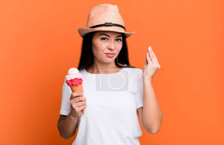 Foto de Hispanic pretty woman making capice or money gesture, telling you to pay. ice cream and summer concept - Imagen libre de derechos