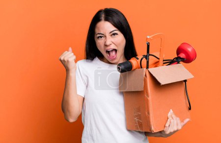 Foto de Mujer bonita hispana sintiéndose conmocionada, riendo y celebrando el éxito con una caja de herramientas - Imagen libre de derechos