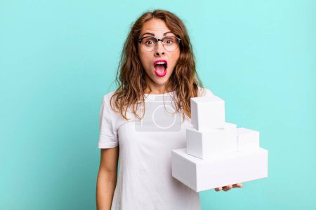 Photo for Hispanic pretty woman looking very shocked or surprised. with white boxes packages - Royalty Free Image