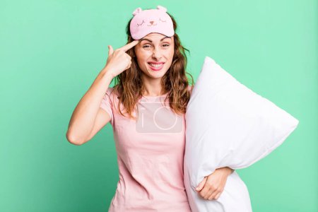 Photo for Hispanic pretty woman feeling confused and puzzled, showing you are insane wearing pajamas and a pillow - Royalty Free Image