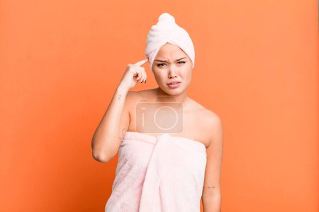 Photo for Hispanic pretty woman feeling confused and puzzled, showing you are insane wearing bathrobe. beauty concept - Royalty Free Image