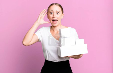 Photo for Caucasian pretty woman screaming with hands up in the air with white boxes packages - Royalty Free Image