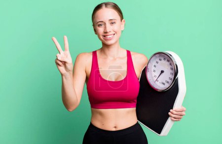 Photo for Caucasian pretty woman smiling and looking friendly, showing number two. fitness and diet concept - Royalty Free Image