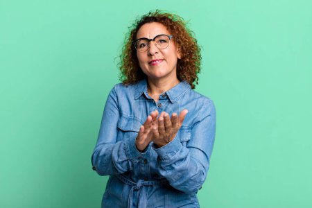 Foto de Mujer hispana de mediana edad sintiéndose feliz y exitosa, sonriendo y aplaudiendo, diciendo felicitaciones con un aplauso - Imagen libre de derechos