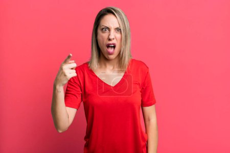 Photo for Blonde adult woman pointing at camera with an angry aggressive expression looking like a furious, crazy boss - Royalty Free Image