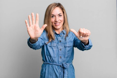 Foto de Blonde adult woman smiling and looking friendly, showing number six or sixth with hand forward, counting down - Imagen libre de derechos