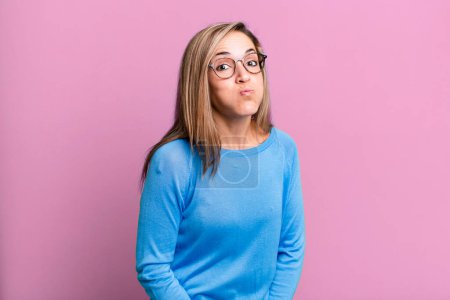 Foto de Blonde adult woman with a goofy, crazy, surprised expression, puffing cheeks, feeling stuffed, fat and full of food - Imagen libre de derechos