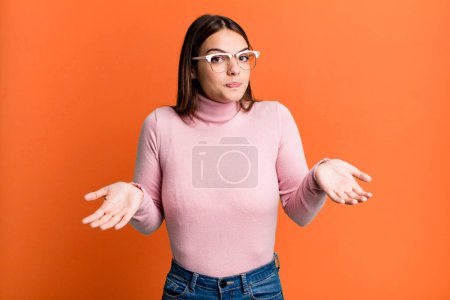 Photo for Pretty young adult woman feeling clueless and confused, having no idea, absolutely puzzled with a dumb or foolish look - Royalty Free Image