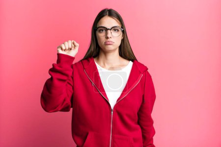 Photo for Pretty young adult woman feeling serious, strong and rebellious, raising fist up, protesting or fighting for revolution - Royalty Free Image