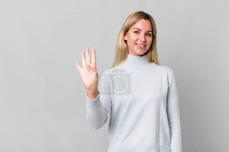Photo for Caucasian blonde woman smiling and looking friendly, showing number four. copy space concept - Royalty Free Image