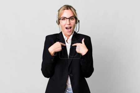 Téléchargez les photos : Caucasian blonde woman feeling happy and pointing to self with an excited. telemarketing cocnept - en image libre de droit