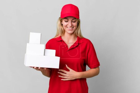 Téléchargez les photos : Caucasian blonde woman laughing out loud at some hilarious joke. delivery boxes - en image libre de droit