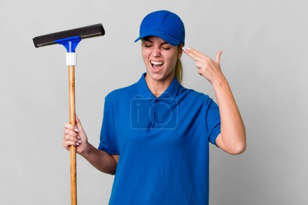 Photo for Caucasian blonde woman looking unhappy and stressed, suicide gesture making gun sign. windows washer concept - Royalty Free Image