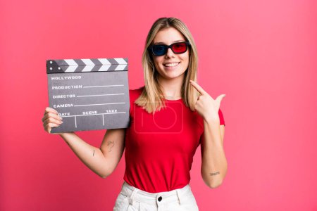 Photo for Young pretty woman smiling confidently pointing to own broad smile. film, cinema and movie concept - Royalty Free Image