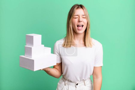 Photo for Young pretty woman shouting aggressively, looking very angry. blank white boxes concept - Royalty Free Image