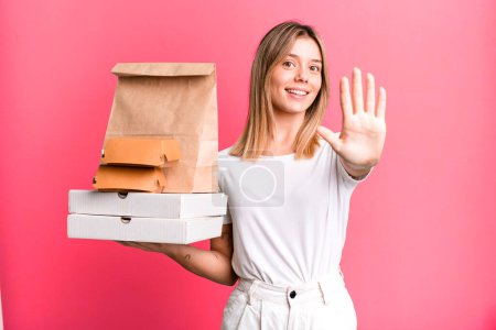 Photo for Young pretty woman smiling and looking friendly, showing number five. delivery and take away food concept - Royalty Free Image