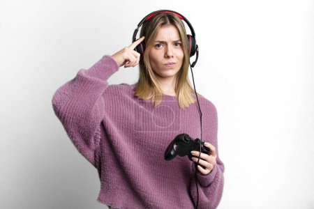 Photo for Young pretty woman feeling confused and puzzled, showing you are insane. gamer with headset and controller - Royalty Free Image