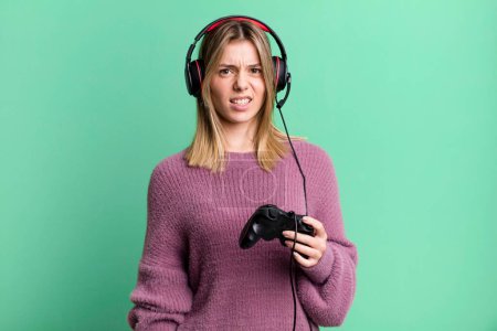 Téléchargez les photos : Young pretty woman feeling puzzled and confused. gamer with headset and controller - en image libre de droit