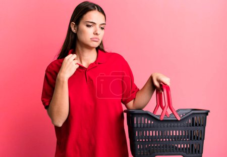 Photo for Young pretty woman feeling stressed, anxious, tired and frustrated. empty shopping basket concept - Royalty Free Image