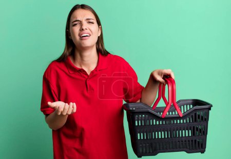 Téléchargez les photos : Young pretty woman looking desperate, frustrated and stressed. empty shopping basket concept - en image libre de droit