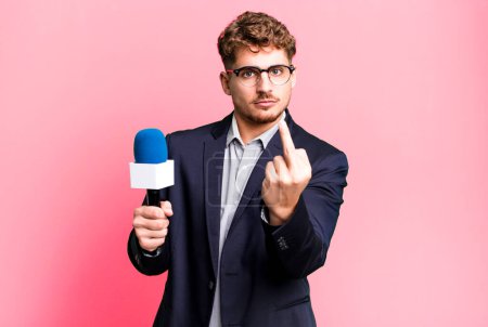 Foto de Joven hombre caucásico adulto sintiéndose enojado, molesto, rebelde y agresivo. periodista o presentador con micrófono - Imagen libre de derechos