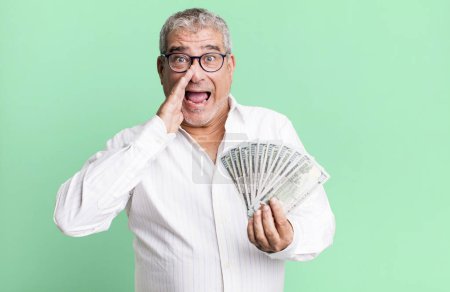 Photo for Middle age senior man feeling happy,giving a big shout out with hands next to mouth. dollar banknotes concept - Royalty Free Image
