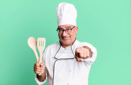 Photo for Middle age senior man pointing at camera choosing you. restaurant chef with a tool concept - Royalty Free Image