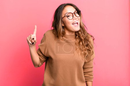 Photo for Young pretty woman feeling like a happy and excited genius after realizing an idea, cheerfully raising finger, eureka! - Royalty Free Image