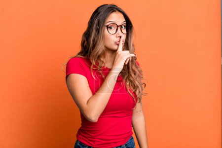 Photo for Young pretty woman asking for silence and quiet, gesturing with finger in front of mouth, saying shh or keeping a secret - Royalty Free Image