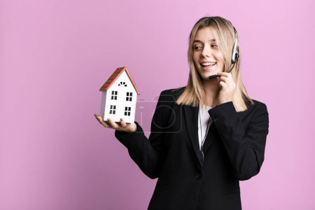 Photo for Young pretty woman with headset and a house model. real state concept - Royalty Free Image