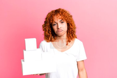 Photo for Red hair pretty woman feeling sad and whiney with an unhappy look and crying. blank packages boxes concept - Royalty Free Image