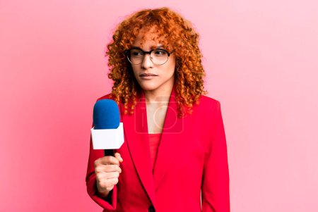 Téléchargez les photos : Red hair pretty woman feeling sad, upset or angry and looking to the side. journalist and presenter concept - en image libre de droit