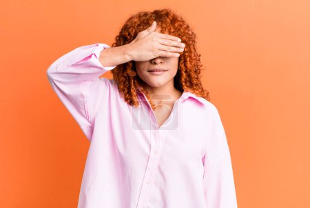 Photo for Redhair pretty woman covering eyes with one hand feeling scared or anxious, wondering or blindly waiting for a surprise - Royalty Free Image