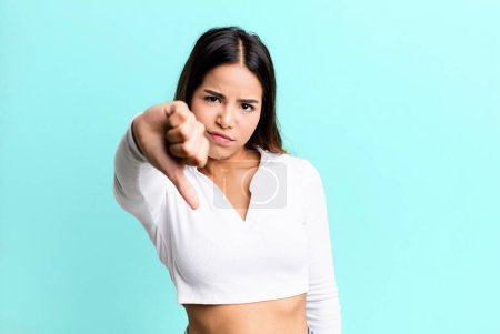 Photo for Hispanic pretty woman feeling cross, angry, annoyed, disappointed or displeased, showing thumbs down with a serious look - Royalty Free Image