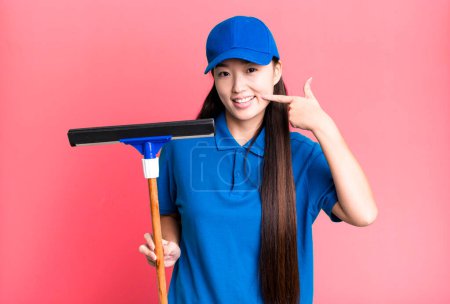 Téléchargez les photos : Pretty asian woman smiling confidently pointing to own broad smile. windows cleaning concept - en image libre de droit