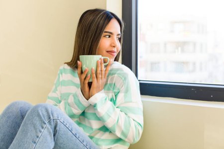 Téléchargez les photos : Jolie femme latine prenant une tasse de café à la maison - en image libre de droit