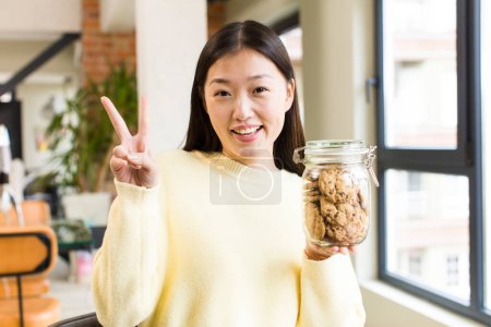 Photo for Asian pretty woman eating cookies at cool living room - Royalty Free Image